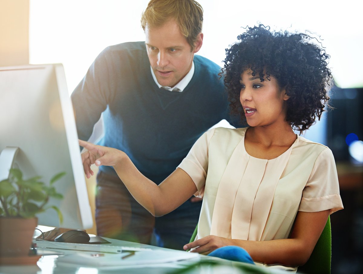 Two coworkers reviewing figures together on a desktop monitor