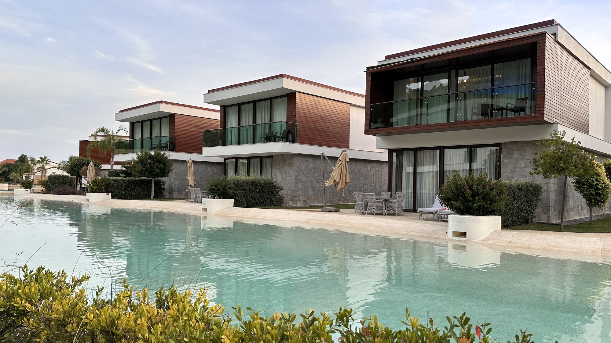 Modern lakeside villas with terraces overlooking a turquoise swimming lagoon