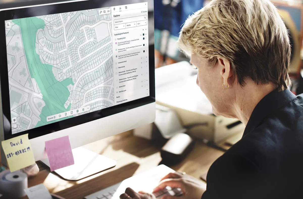 A planner reviewing a property and flood-risk map on a desktop screen